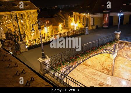 Sibiu, Romania - May 26, 2019: Liars Bridge (Podul Minciunilor) in Sibiu - view from above at night, with red flowers and street lamps glowing. Popula Stock Photo