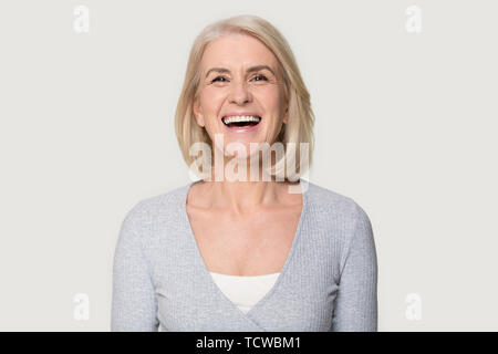 Headshot happy aged female laughing posing on grey studio background Stock Photo