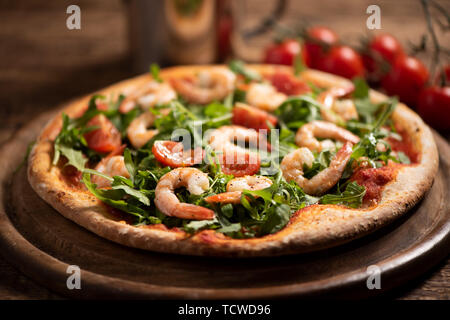 Pizza covered with roquette and shrimps on wooden table close up Stock Photo