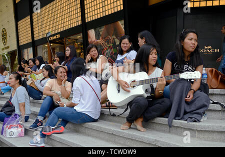 singapore - 2018.02.25:  philippine maids spending time during their only free day on sunday on orchard road in front of ion shopping mall Stock Photo