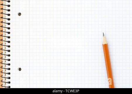 Spiral blank notebook in the cell with pencil. Close up, top view. School concept. Stock Photo