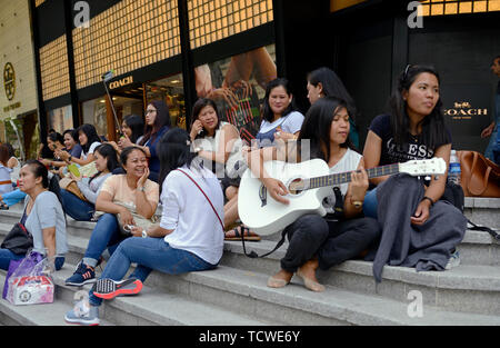 singapore - 2018.02.25:  philippine maids spending time during their only free day on sunday on orchard road in front of ion shopping mall Stock Photo