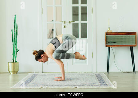 Young attractive smiling woman practicing yoga in a large, bright room Stock Photo