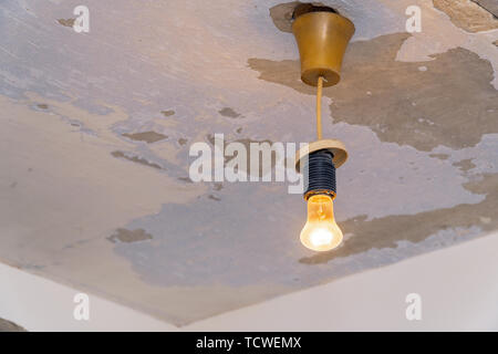 Light bulb hanging on the background of shabby ceiling Stock Photo