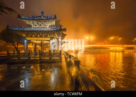 Photographed in the Stele Pavilion of the Wuxi Canal, the canal flows quietly in the night, and the endless transport ships pass quietly under the Xishan Bridge. At the moment, the light rain in Wuxi, mixed with fog, looks dreamy and mysterious against the light. Stock Photo