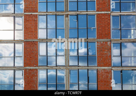 Facades of a multistory building under construction. Construction site, tools, wheel barrow, sand and bricks at new house building, cement mixer machi Stock Photo