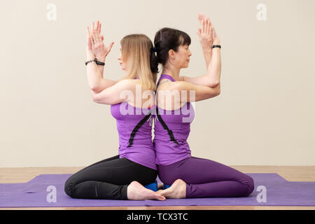 A group of young sports people practicing yoga lesson with an instructor. Fitness club instructors show a master class. Sporty young girls. Stock Photo