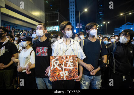 A demonstrator displays a placard which reads 'Anti extradition to China.' In the early hours of 10th of June hundreds of demonstrators clashed with the police as the demonstrators attempted to occured the entrance of the legislative council building where the legislative council members are set to vote on the extradition bill on the 12 of June. The clashes has caused at least 15 people injured including protesters, police officer and members of the press. Hundreds of thousands of demonstrators took to the street of Hong Kong on the 9th of June before the clashes happened to protest against th Stock Photo