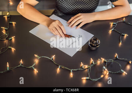 Good morning. Calligrapher Young Woman writes phrase on white paper. Inscribing ornamental decorated letters. Calligraphy, graphic design, lettering Stock Photo