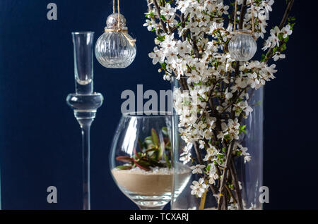 Original wedding flower decorations in the form of mini-vases and bouquets of flowers, hanging on a flowering branch Stock Photo