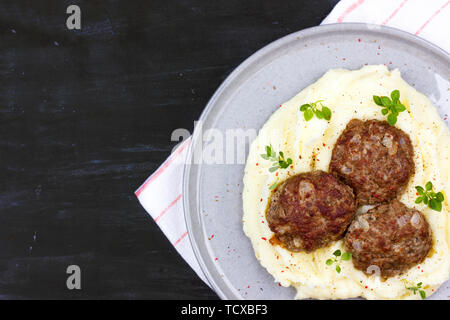 Mashed potatoes and meat balls on gray plate, decorated with fresh basil Stock Photo