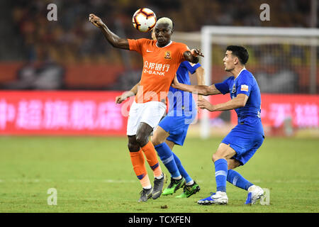 Ivorian football player Jean Evrard Kouassi, left, of Wuhan Zall challenges players of Henan Jianye in their 4th round match during the 2019 Chinese Football Association Super League (CSL) in Wuhan city, central China's Hubei province, 8 June 2019.  Wuhan Zall played draw to Henan Jianye 0-0. Stock Photo