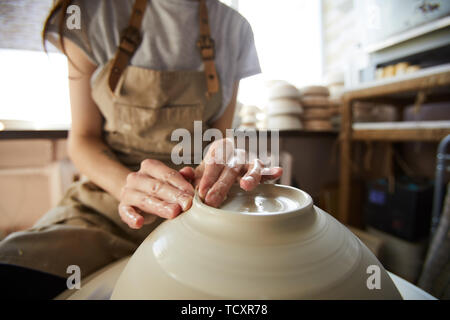 Close up of unrecognizable female artisan shaping bowl on potters wheel, copy space Stock Photo