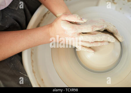 High angle closeup of female potter shaping clay on wheel while working in studio, copy space Stock Photo
