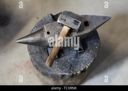 Directly above view of hammer for shaping metal placed on steel anvil in workshop, smithy background Stock Photo