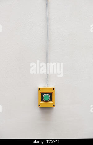 Green In Service button signal on the painted white wall. Concept of system fully operational, anything in service and good order Stock Photo
