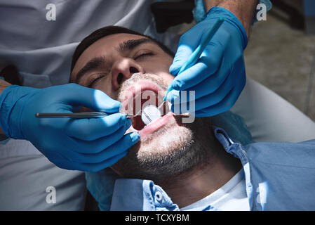 Cropped view of dentist checking up patient's teeth using mouth mirror and dental explorer. Dental tools. Treatment. Modern dental clinic. Horizontal  Stock Photo