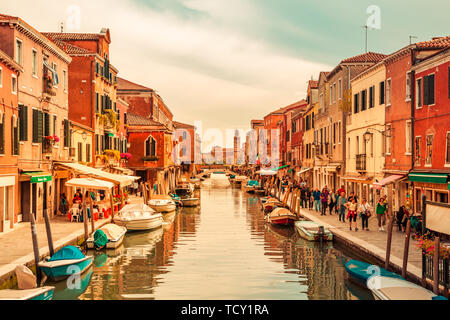 Venice Italy - May 25, 2019: View on Murano island with the central canal, bridge, boats, shops and tourists during sunset Stock Photo