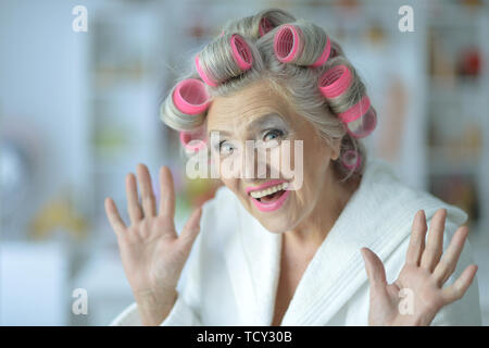 Portrait of senior woman in bathrobe with curlers Stock Photo