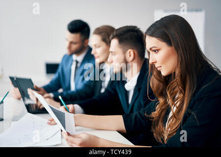 Portrait of smiling group of business people sitting in row together at table in a modern office. Business team concept Stock Photo