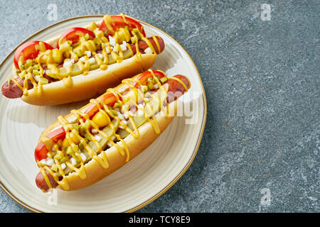 Dish with two hot dogs on stone table Stock Photo