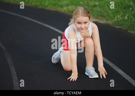 happy little girl running on the stadium Stock Photo