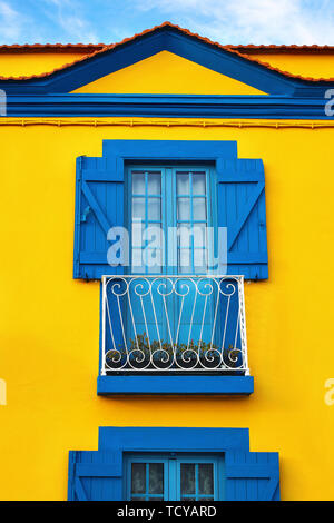 Closeup of colorful Portuguese yellow house facade with old blue windows and wooden shutters in Portugal town, Europe. Travel and architecture concept Stock Photo