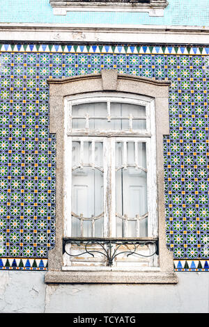 Closeup of traditional Portuguese house facade decorated by beautiful ceramic azulejo tiles Old white wooden window on tile painted wall. Portugal Stock Photo