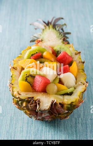 Mix fruit served inside pineapple on blue background Stock Photo