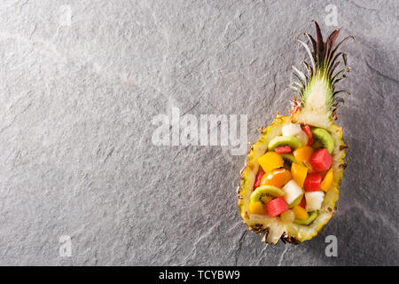 Mix fruit served inside pineapple on blue background Stock Photo