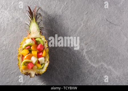 Mix fruit served inside pineapple on blue background Stock Photo
