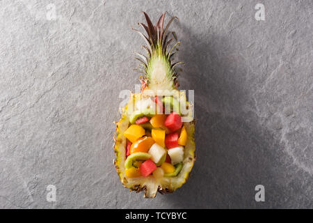 Mix fruit served inside pineapple on blue background Stock Photo
