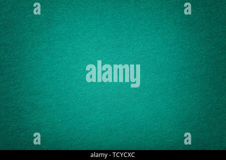 Dark turquoise matte background of suede fabric, closeup. Velvet texture of seamless green woolen felt with vignette. Stock Photo