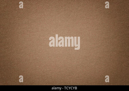 Light brown matte background of suede fabric, closeup. Velvet texture of seamless umber woolen felt with vignette. Stock Photo
