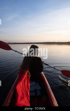 Back view of happy cute girl holding paddle in a kayak on the river Stock Photo