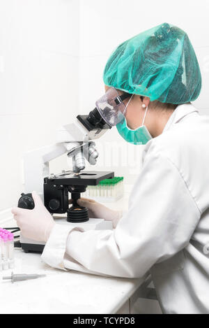 Young female scientist in modern laboratory, using microscope .  Stock Photo