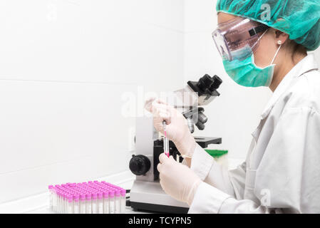 Young female scientist in modern laboratory, using microscope .  Stock Photo