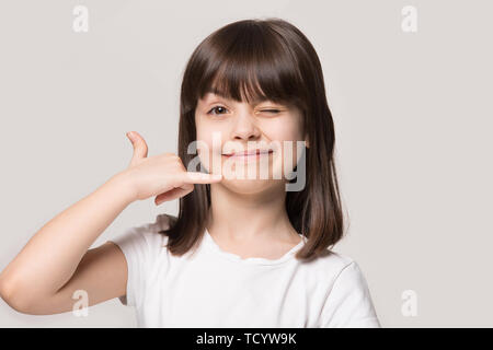 Little funny girl makes call me hand gesture studio shot Stock Photo