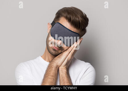 Man wearing mask sleeping on folded hands studio shot Stock Photo