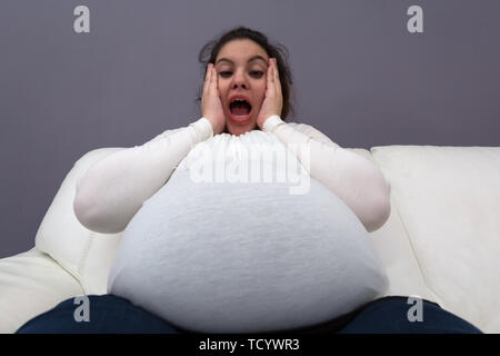 Foto de Shocked plus size model girl sitting on a bed and looking