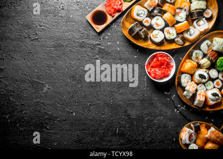 Types of sushi, Maki and rolls served on plates. On black rustic background