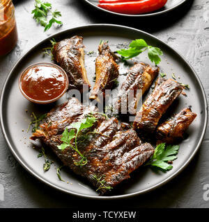 Close up of grilled spare ribs on plate over black stone background. Tasty bbq meat. Stock Photo