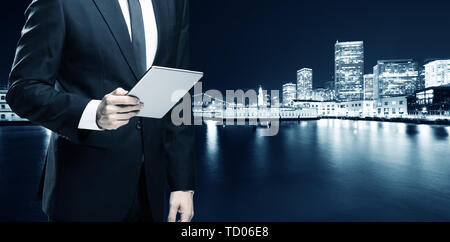 businessman with tablet with modern buildings near water in san Stock Photo