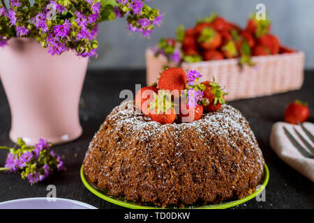 Pound cake with strawberries and flowers in vase on the background. Stock Photo
