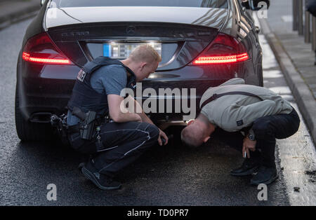 07 June 2019, Hessen, Frankfurt/Main: A police officer (l) of the 'Autoposer Raser Tuner Control Unit' (KART) next to the driver of the Mercedes CLS 550 uses a flashlight to point to the manipulated exhaust system for which the vehicle was seized. (Zu dpa 'Control unit KART on tour - expensive evening for Poser') Photo: Boris Roessler/dpa - ATTENTION: The number plate was pixelated for legal reasons Stock Photo
