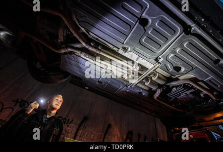 07 June 2019, Hessen, Frankfurt/Main: On the hook of a tow-away vehicle hangs a secured Mercedes, the underside of which is illuminated by a torch of a police officer of the 'Control Unit Autoposer Raser Tuner' (KART), so that the manipulated and therefore booming exhaust system becomes visible. (Zu dpa 'Control unit KART on tour - expensive evening for Poser') Photo: Boris Roessler/dpa Stock Photo