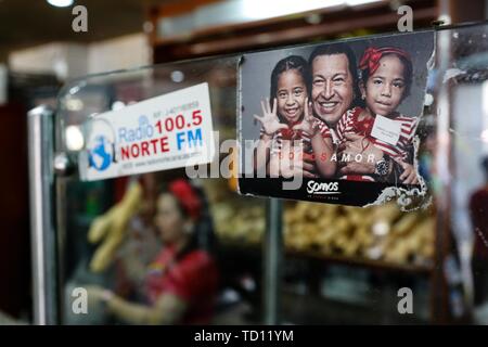 05 June 2019, Venezuela, Caracas: 'We are love', stands under the picture of the late President Hugo Chavez (M.) with two children in the bakery 'La Minka' run by government supporters. All employees have learned the profession in the bakery. The youngest has been part of the team for 15 days. The former private bakery was called 'Mansion's Bakery'. Now around 6,000 pieces of bread are produced there every day at prices set by the state. The country with the largest oil reserves in the world is in a dramatic decline. Money devaluation is the highest in the world, for many people food is unaffo Stock Photo