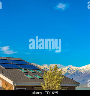 Square frame Roof with solar panels and skylights against lake and mountain under blue sky Stock Photo