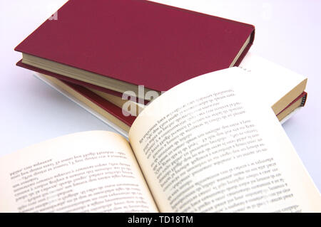 An open book with other books of different colors in the background on white background Stock Photo