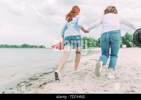 Two young women friends running on the beach. Back view. Stock Photo